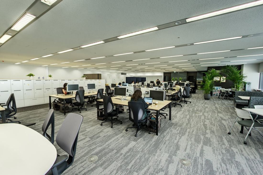Obayashi: Open office with grey carpet, desks and lockers along the wall