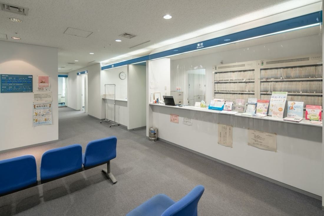 Obayashi: Reception counter with blue waiting chairs in a white corridor