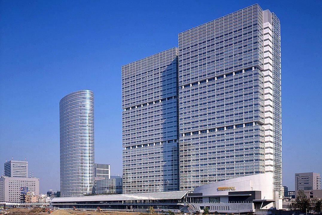 Obayashi: Two grid-faced glass towers beside a rounded tower under a clear sky