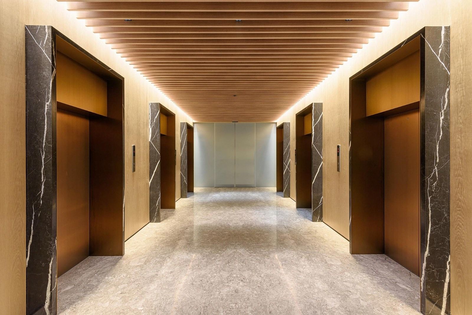 Oberoi Realty: A long elevator lobby with wood walls and marble frames