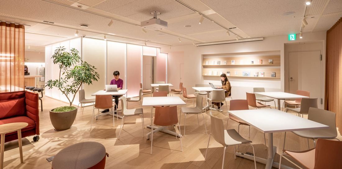 Okamura: Bright workspace with white tables, a potted tree and a high-back booth