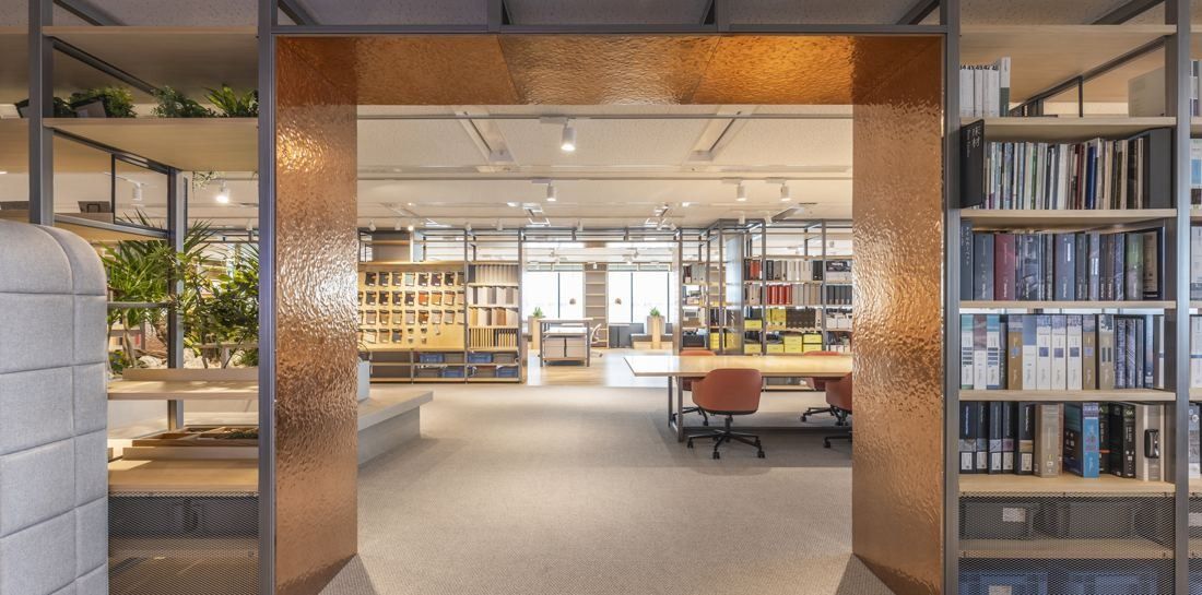 Okamura: Copper-clad doorway opening onto shelves of material samples and worktables