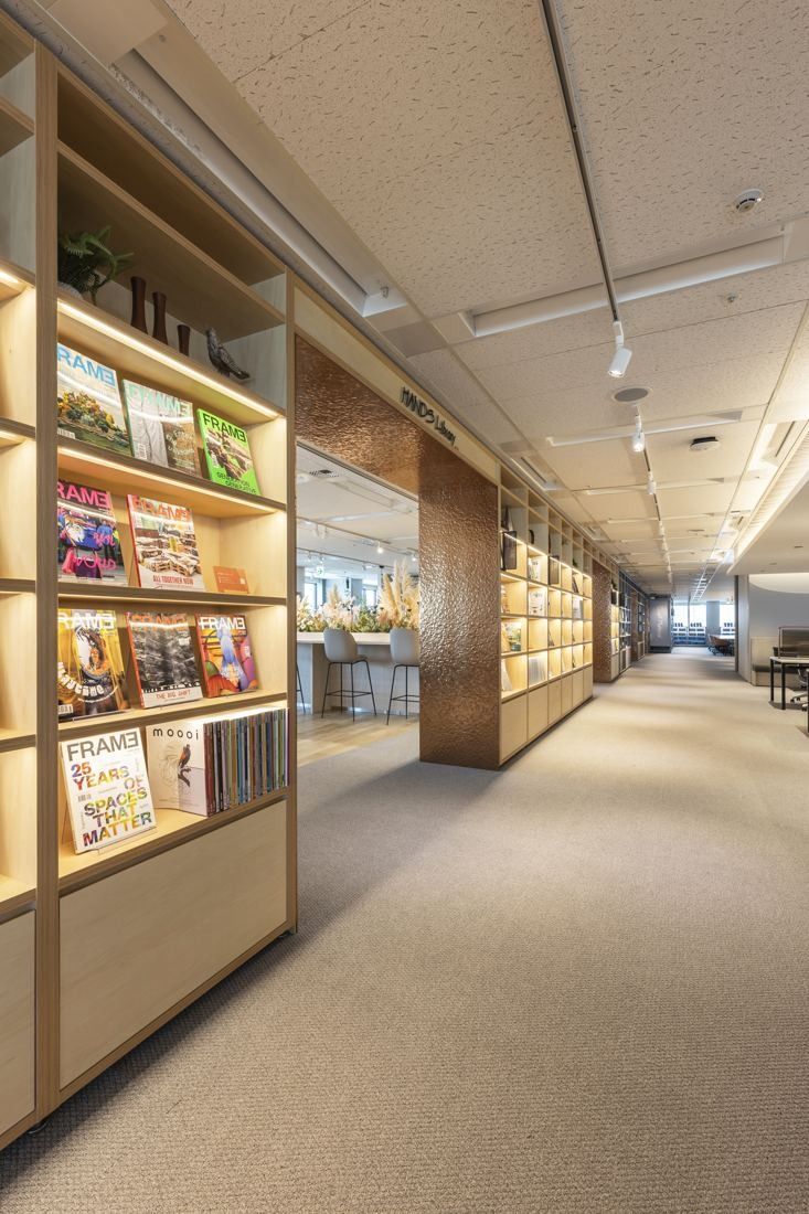 Okamura: Corridor lined with lit shelves of books and samples