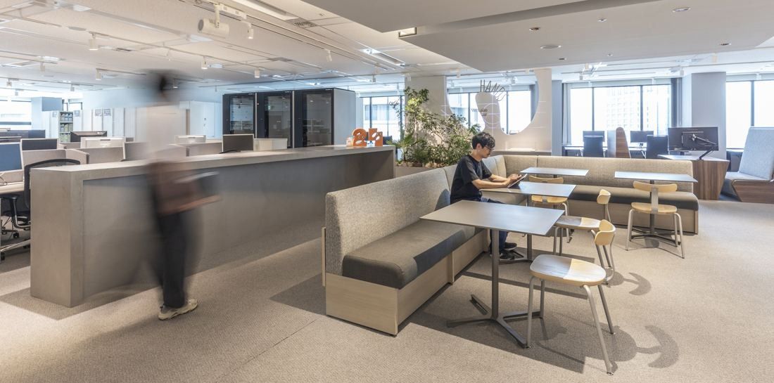 Okamura: Counter and booth seating in an open office with a figure in motion blur