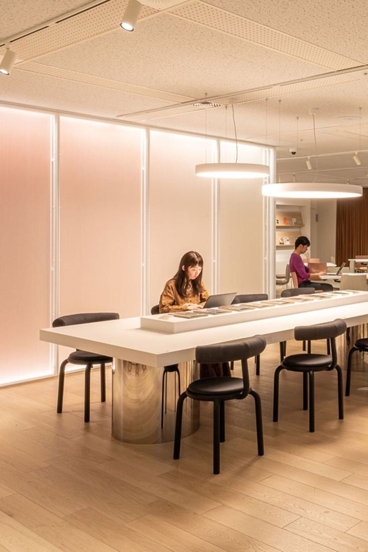 Okamura: Long white table with black stools under ring lights