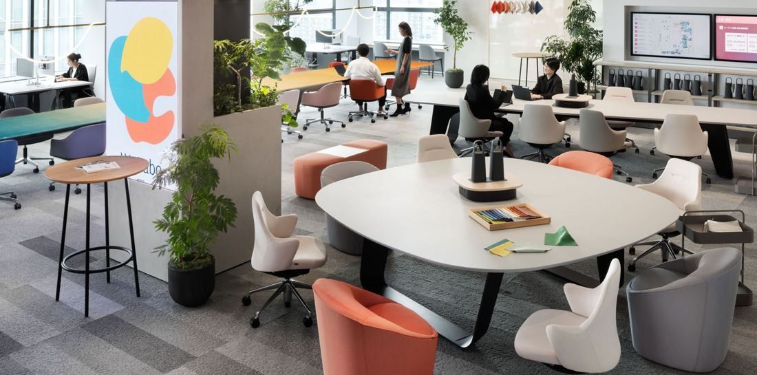 Okamura: Open office with a rounded white meeting table, colourful chairs and plants