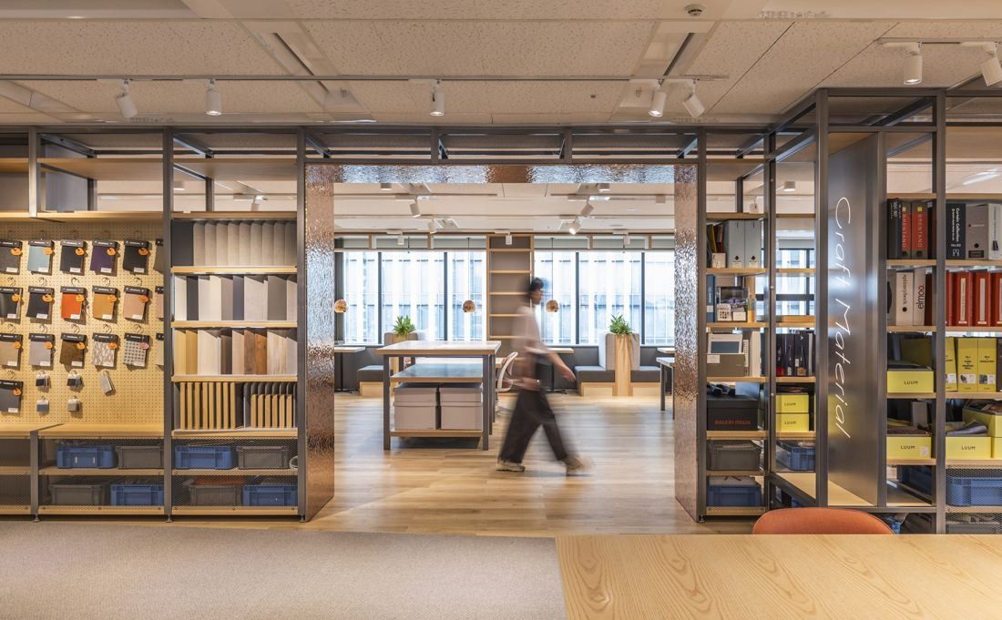 Okamura: Open shelving frames filled with material samples and books framing a workroom
