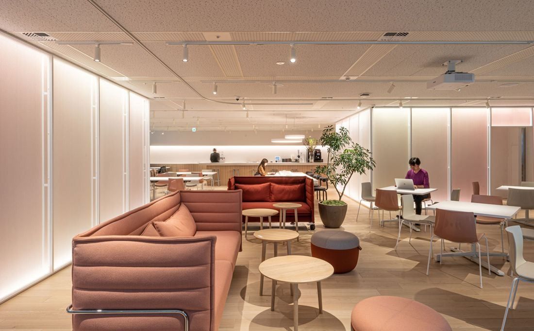 Okamura: Soft pink-lit lounge with upholstered high-back sofas and small round tables