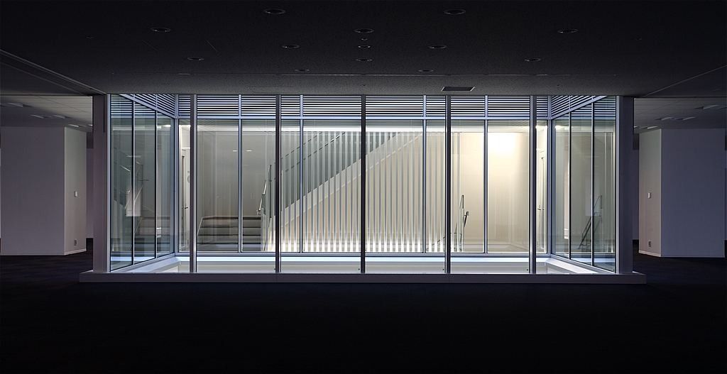 Olympus: Brightly lit glass-walled stair hall seen at night