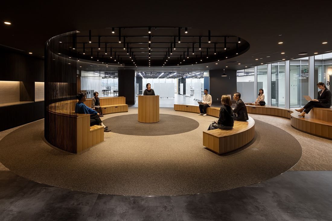 Olympus: Dark circular space with curved wooden bench seating around a central lectern