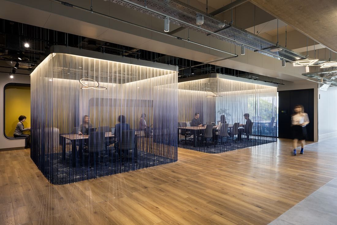 Olympus: Meeting areas enclosed by curtains of hanging blue cords on a wooden floor