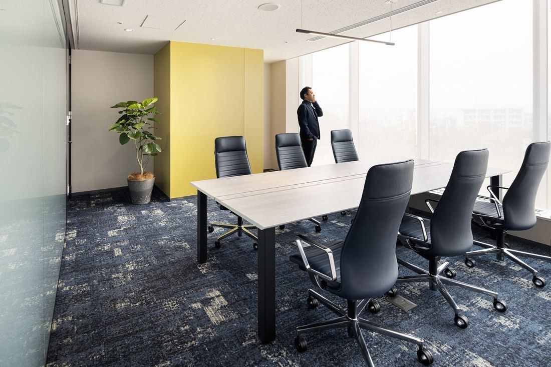 Olympus: Meeting room with a long table, black high-back chairs and a yellow wall