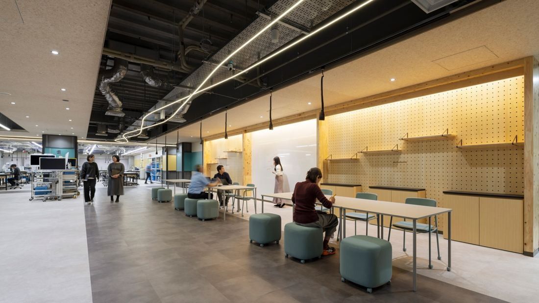 Olympus: Open floor with stools, long tables and a pegboard wall, lab equipment in the background
