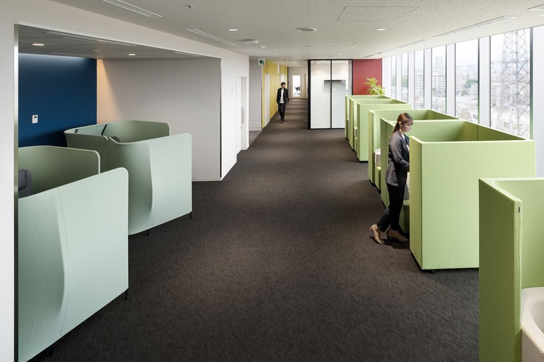 Olympus: Row of pale green high-backed booths along a carpeted aisle by the windows