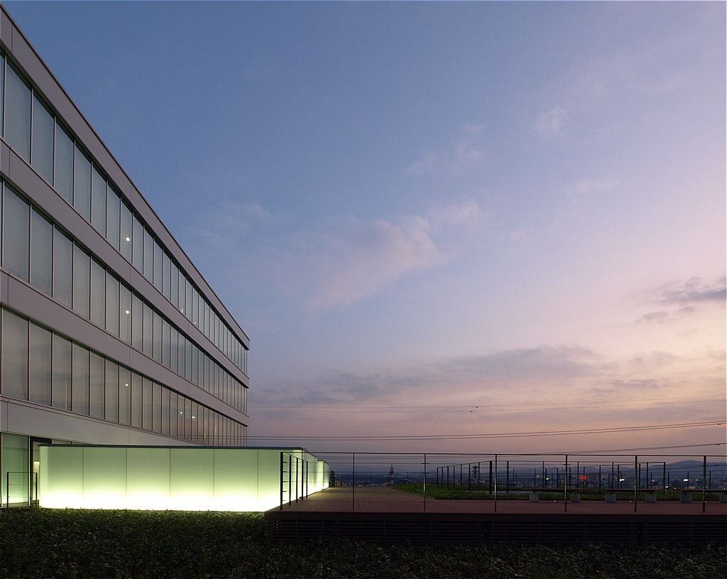 Olympus: Side of the building at dusk with a glowing glass base