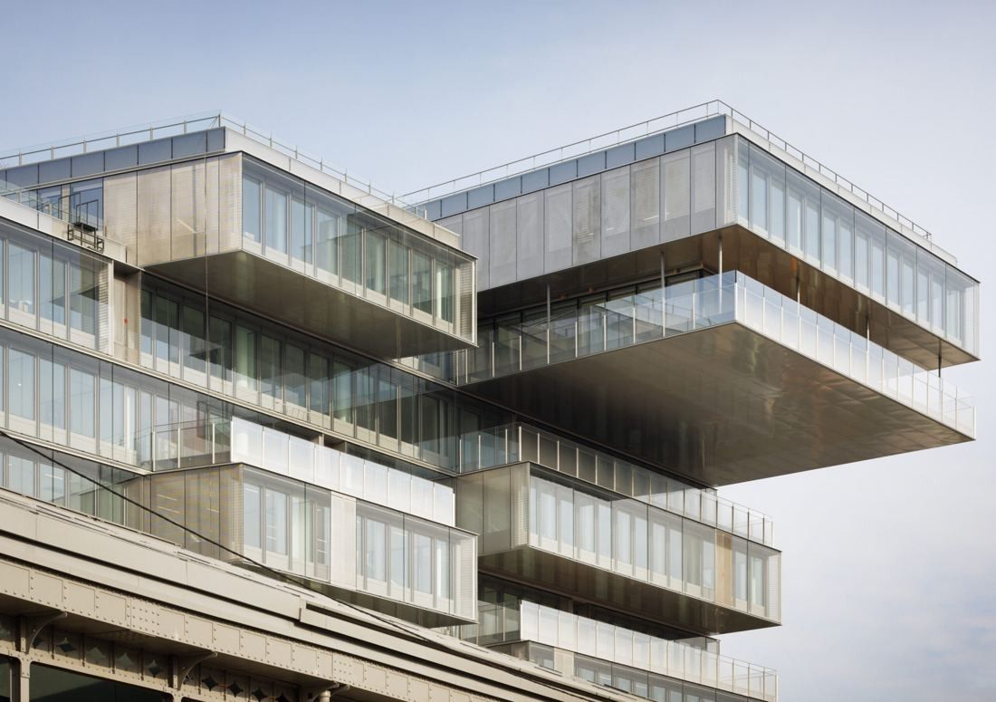 Orange: Boxy glass volumes cantilevering out from the top of the building against a pale sky
