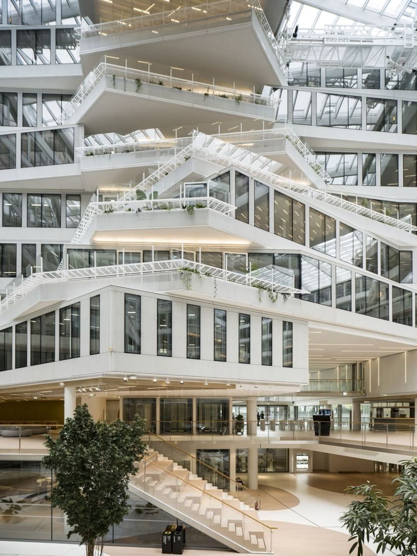 Orange: Stacked white floors with stairs and walkways rising through a tall glass-roofed atrium