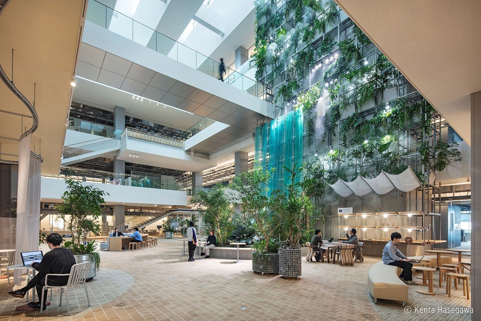 Panasonic: Atrium with a green wall, tall plants and people at tables