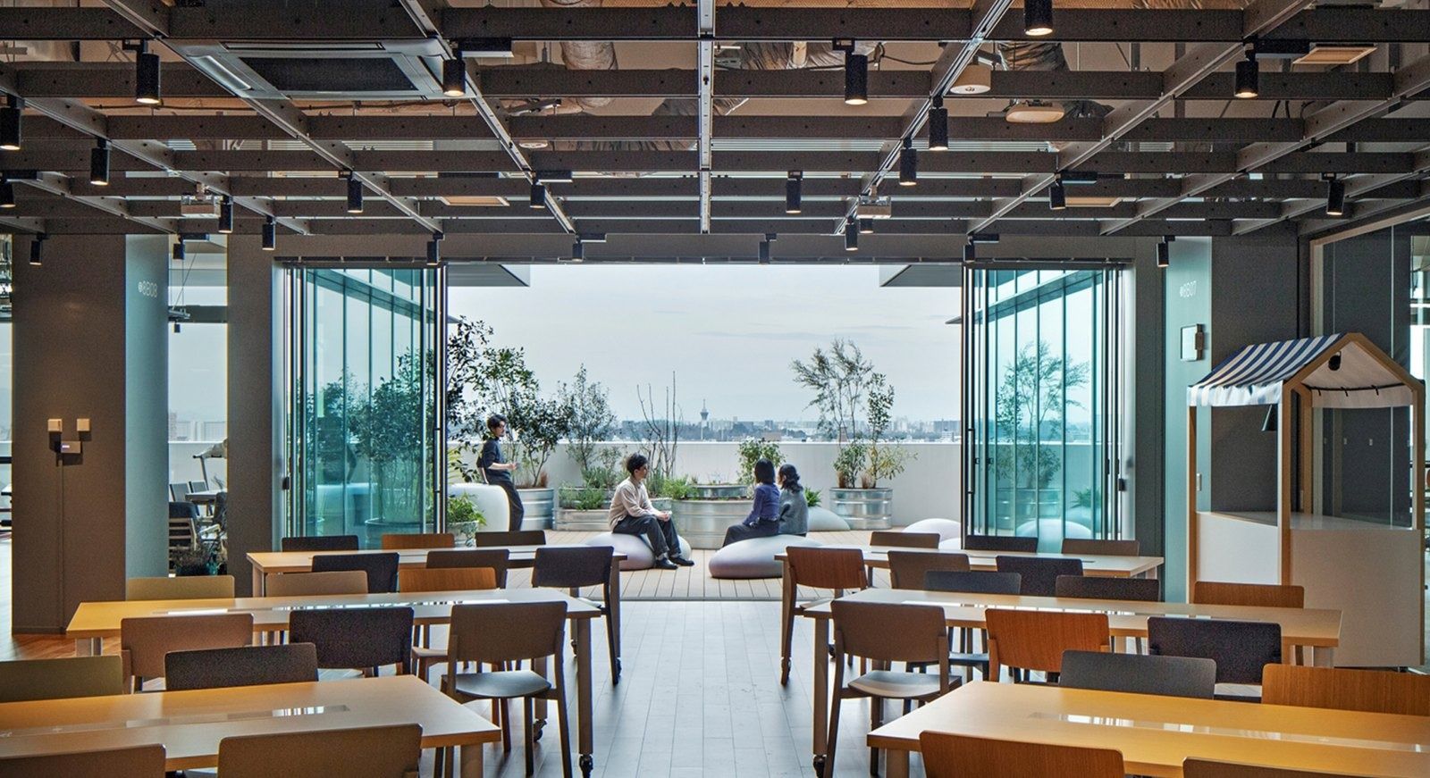 Panasonic: Dining tables by a glass wall with a planted terrace beyond