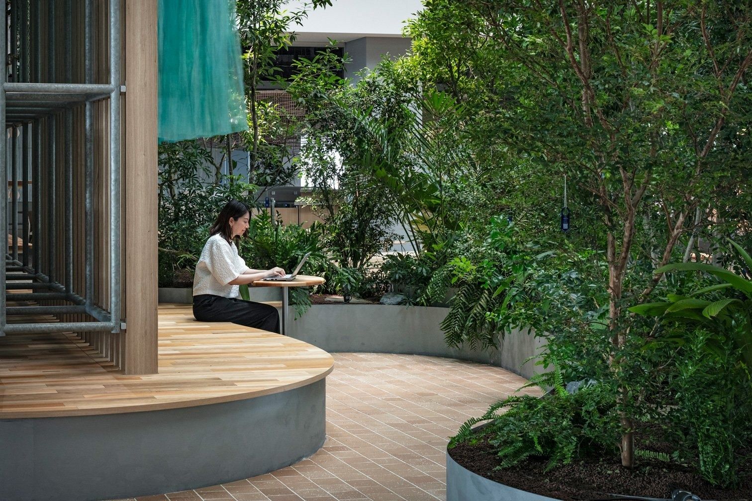 Panasonic: Round timber bench around a planter among dense plants