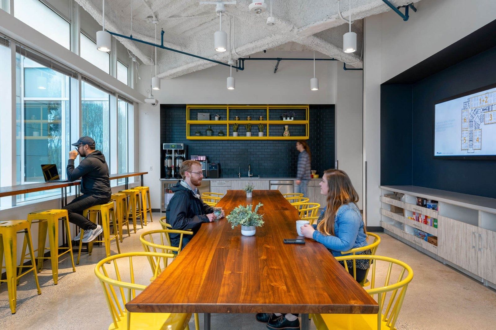 PayPal: A long wooden table with yellow chairs