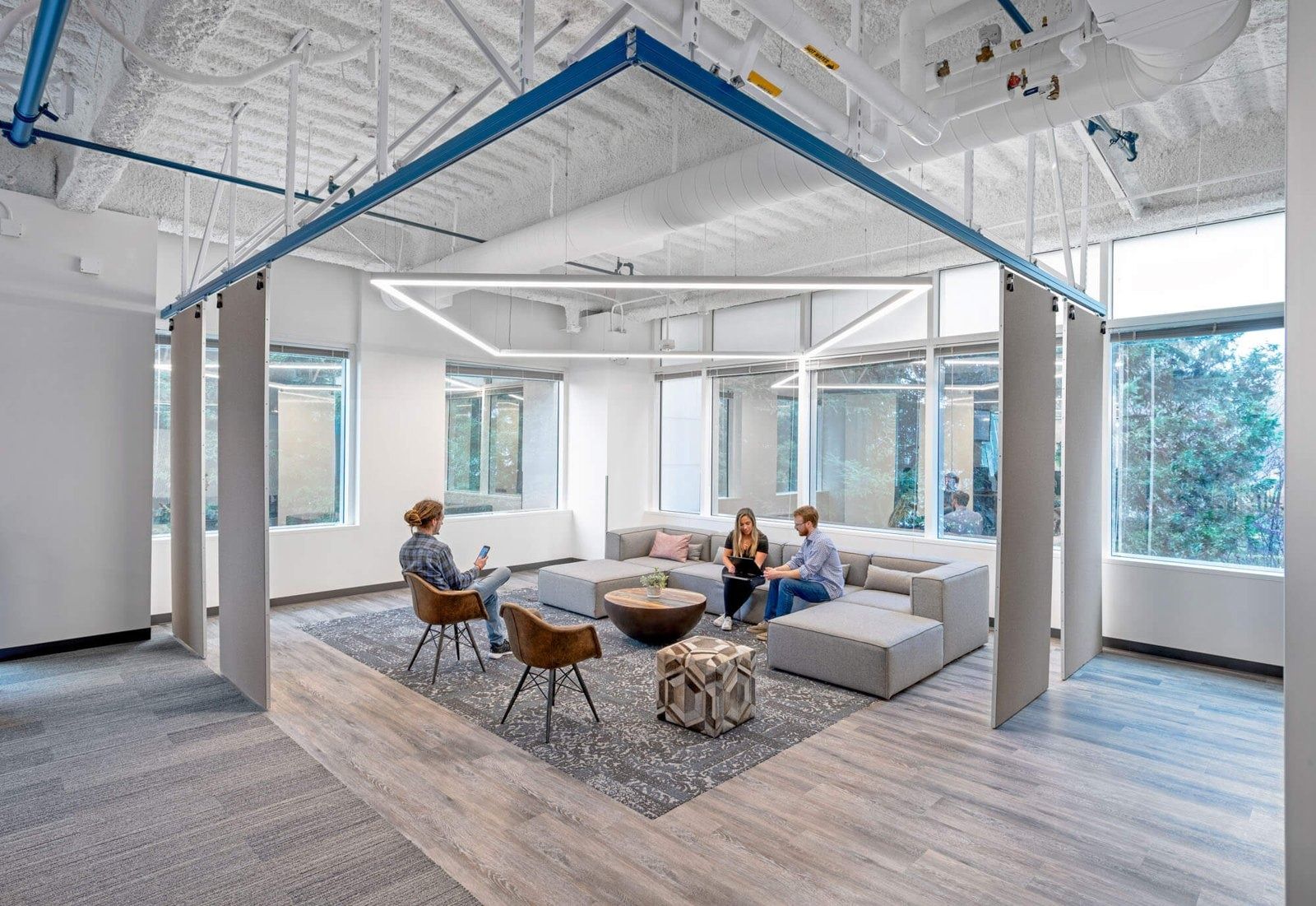 A lounge framed by blue steel beams in a bright office