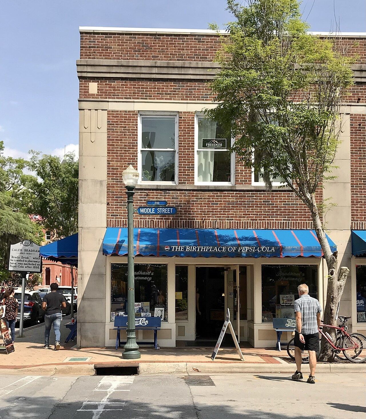 Brick corner building with a blue awning reading Birthplace of Pepsi-Cola