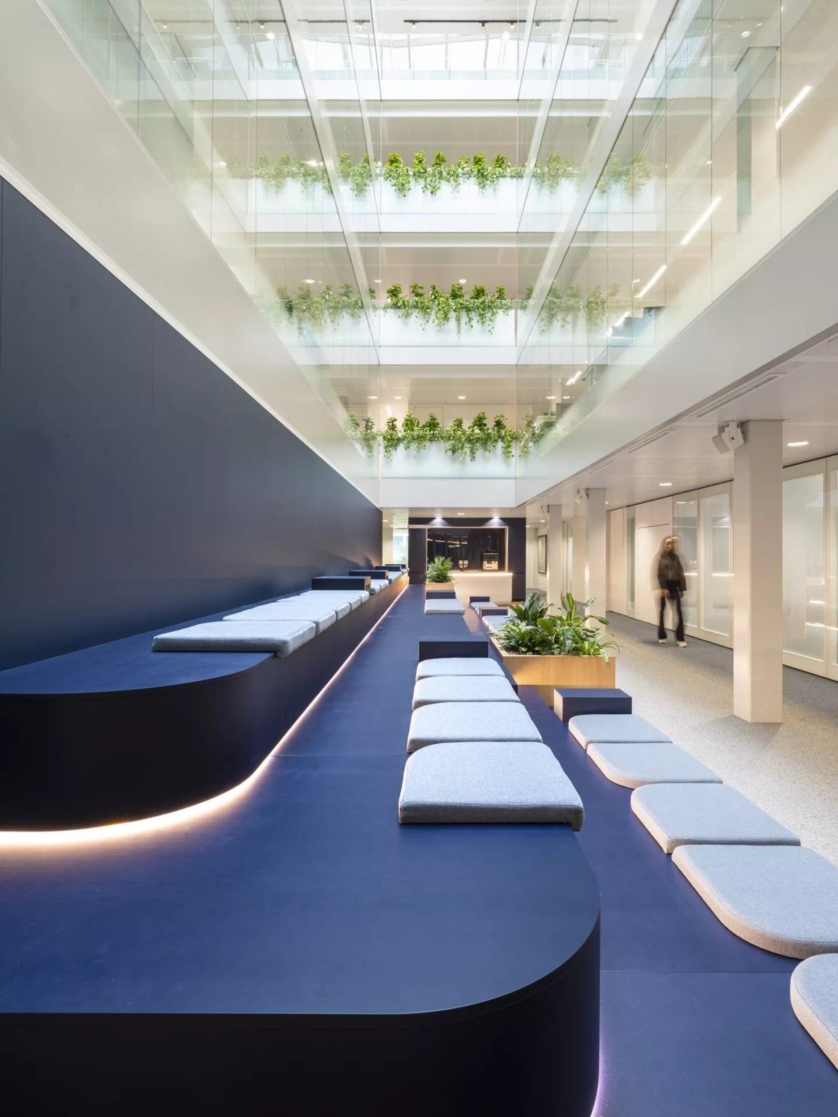 Long blue lounge bench under a skylit atrium