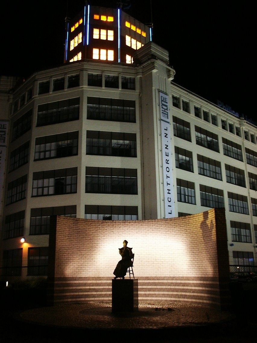 White factory building with a lit glass tower
