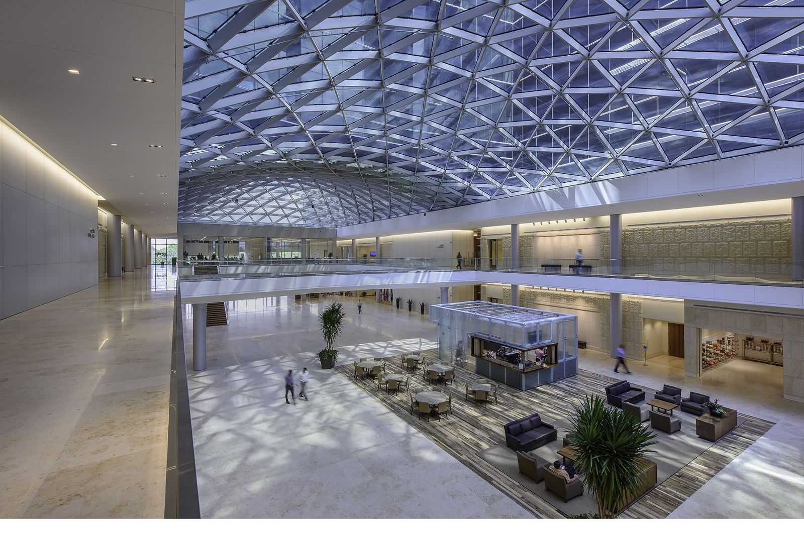 A gathering hall under a vast patterned glass skylight