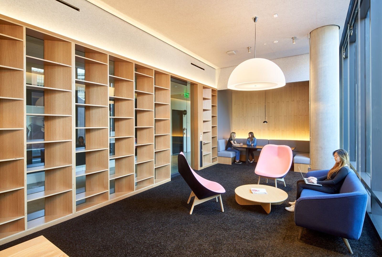 Pinterest: A library lounge with tall wooden shelves and pink chairs