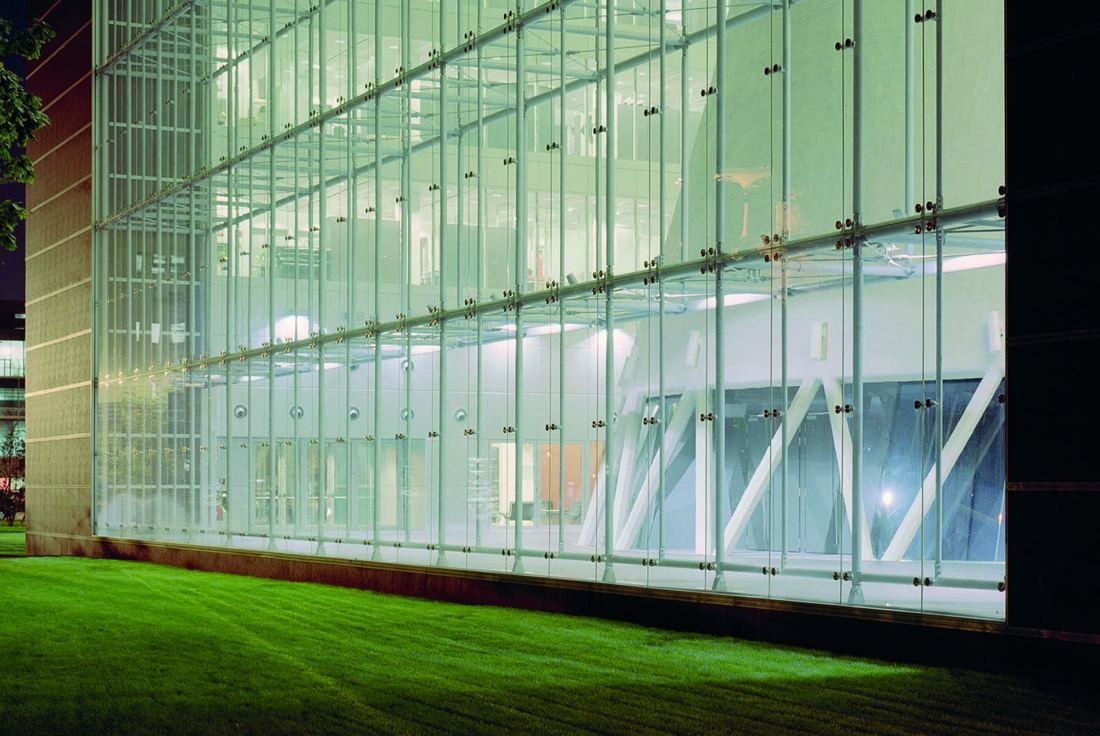 Pirelli: Lit glass curtain wall with diagonal steel bracing above a lawn at night