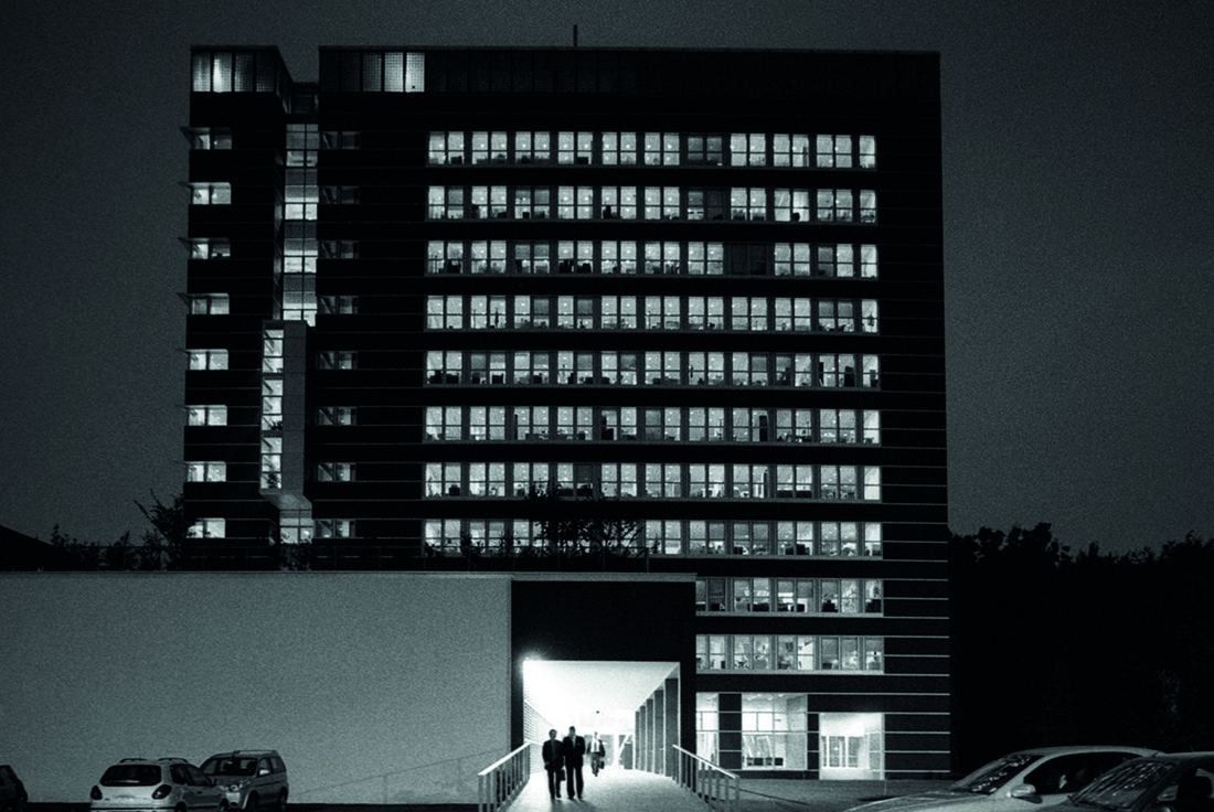 Pirelli: Office block with lit windows at night and an entrance passage at ground level