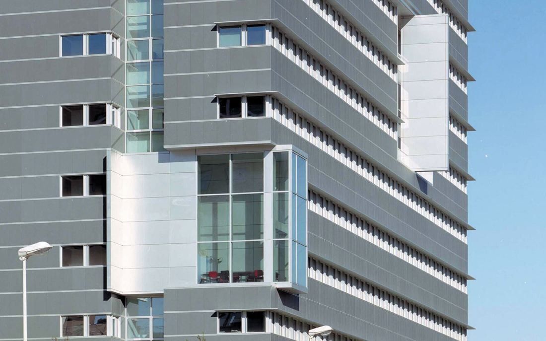 Pirelli: Pale stone-clad façade with projecting glazed bays against a blue sky