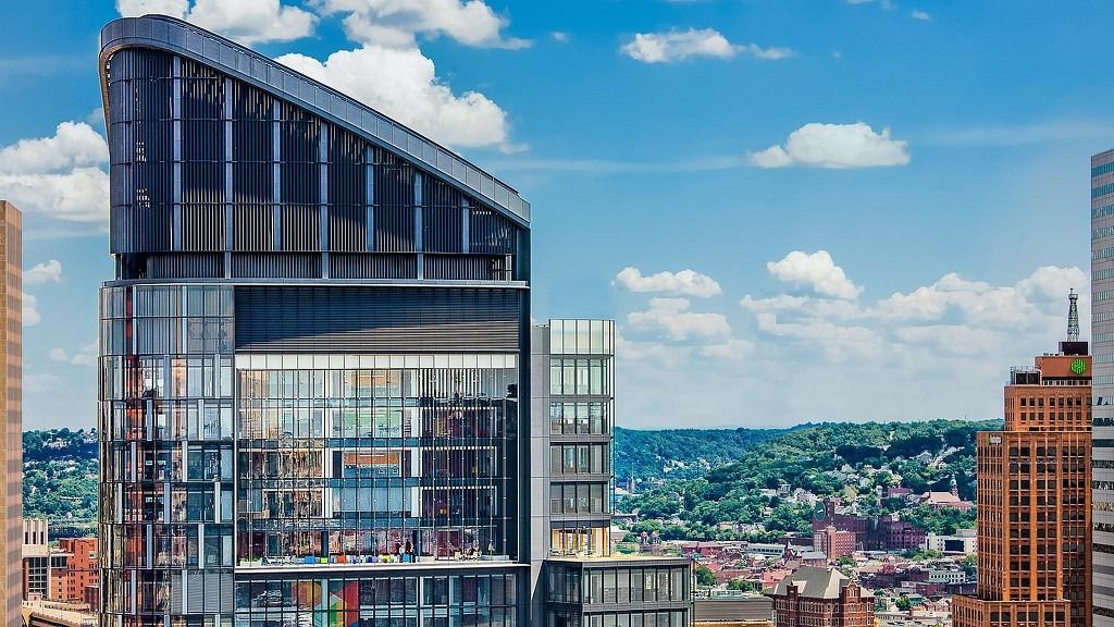 Top of a glass tower with Pittsburgh's hills behind it