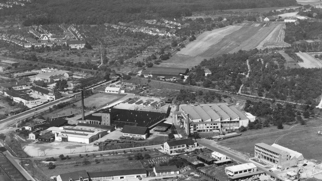 Black-and-white aerial view of factory halls, a chimney and fields around the Zuffenhausen works