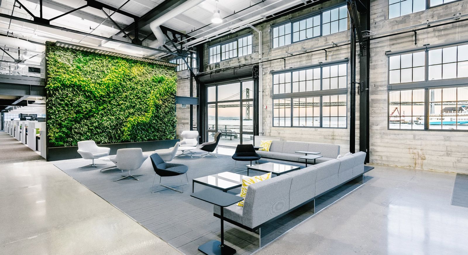 Prologis: A lounge with grey sofas in front of a tall green living wall inside a steel-trussed warehouse space