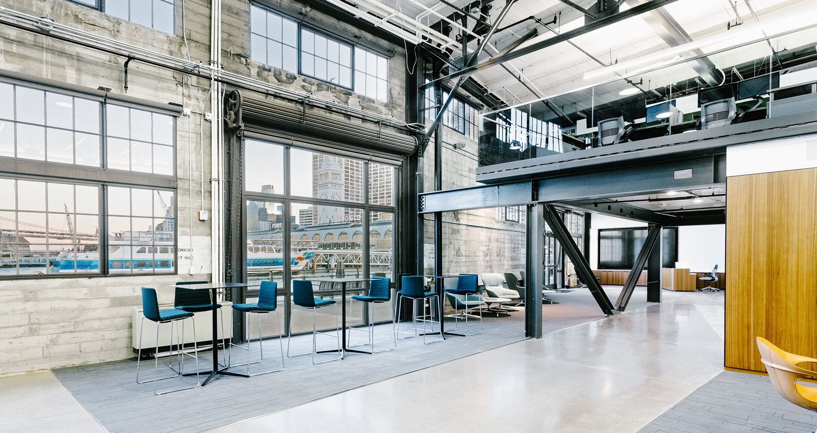 Prologis: High tables by tall industrial windows under exposed steel beams and a mezzanine