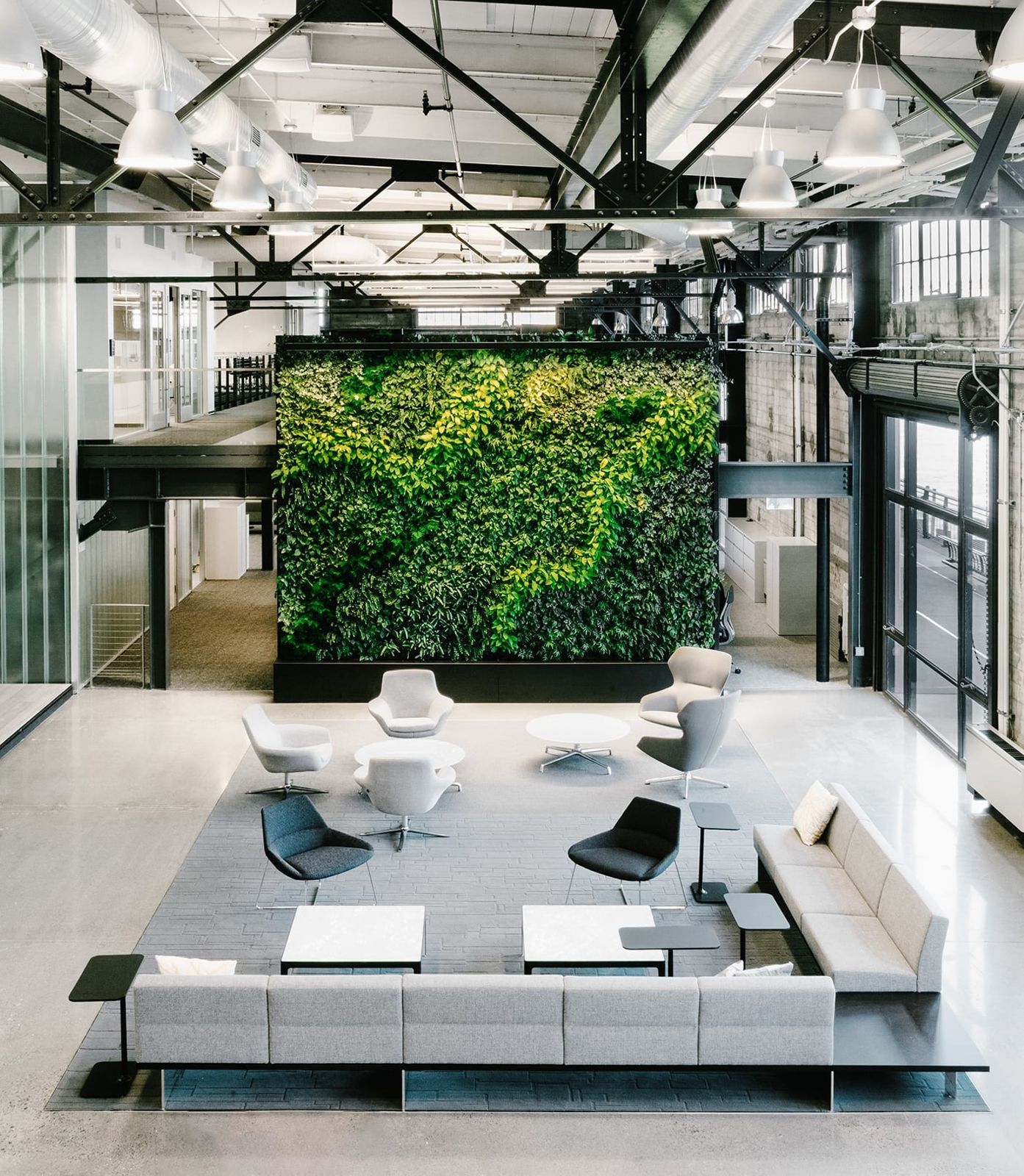 Prologis: Seating arranged around a living wall under exposed steel trusses