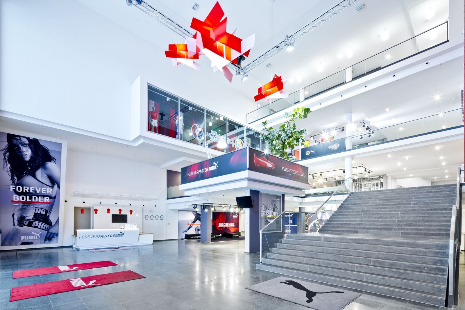 PUMA: Bright atrium with a broad stair and red hanging installations
