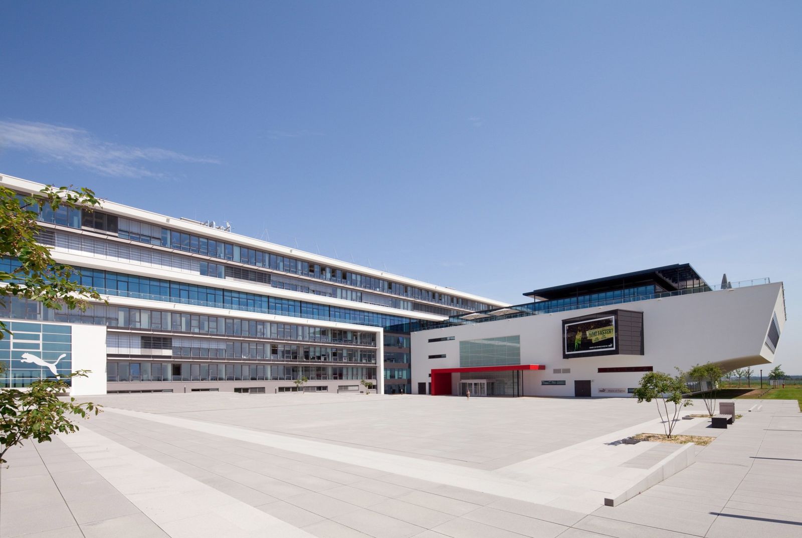 PUMA: Long white office building beside a paved plaza