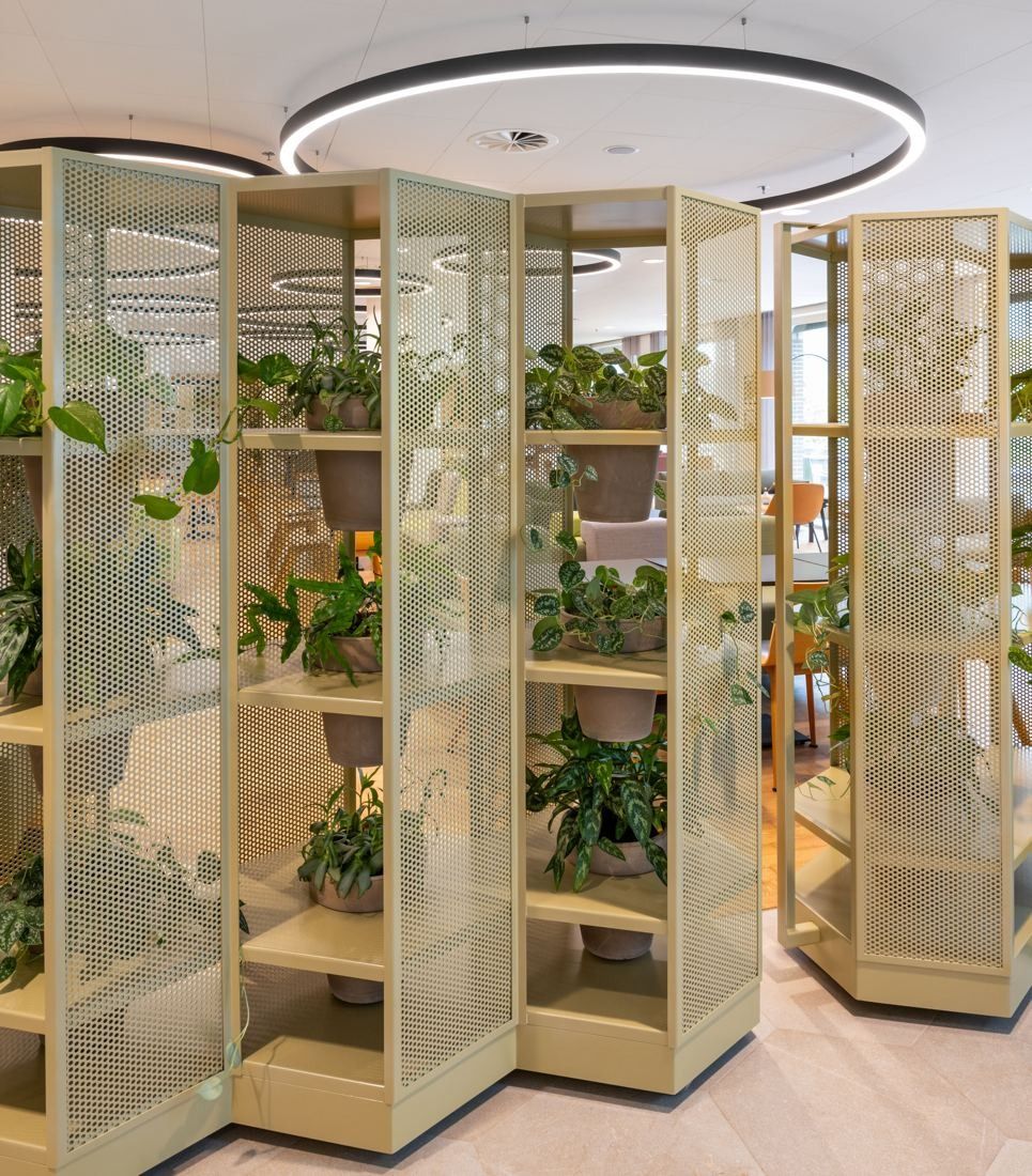 Rabobank: Tall freestanding shelving units with mesh panels holding potted plants