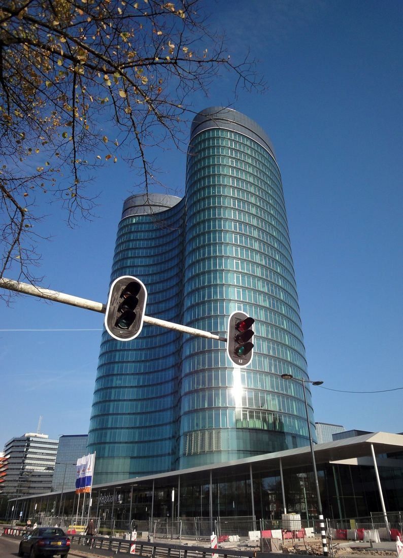 Rabobank: The glass towers catching low sun, with a traffic light in the foreground