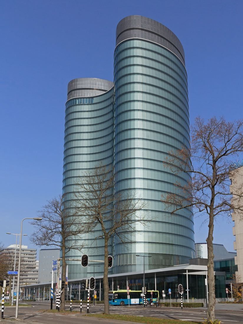 Rabobank: The glass towers rising behind bare trees and a street with a bus stop