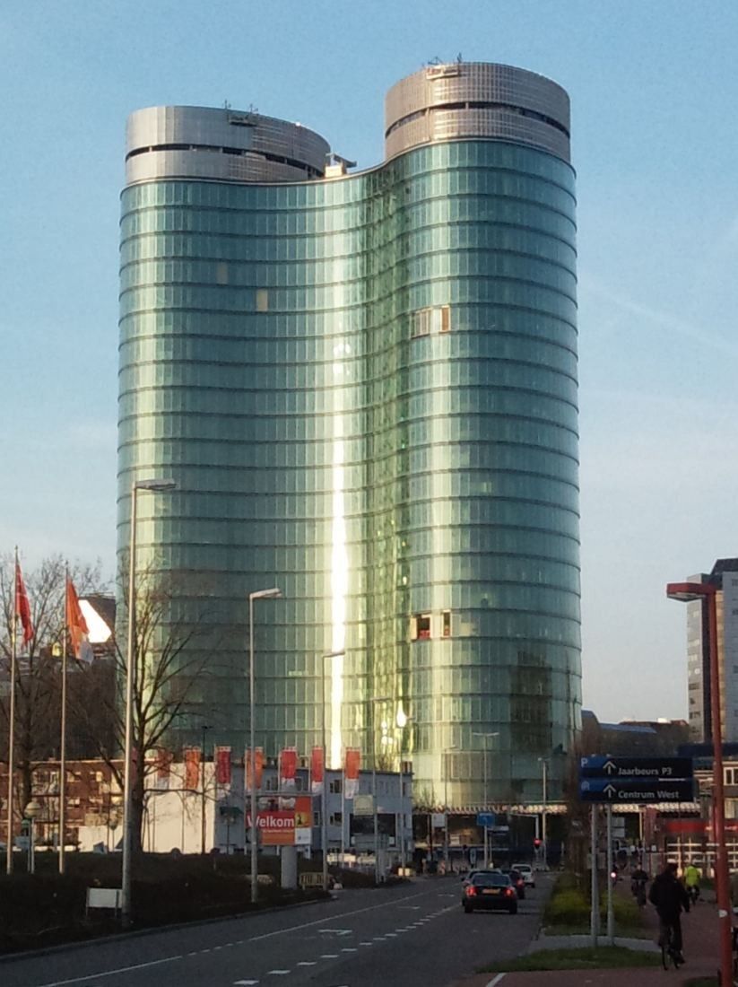 Rabobank: The two glass towers seen down a street with flags and parked cars