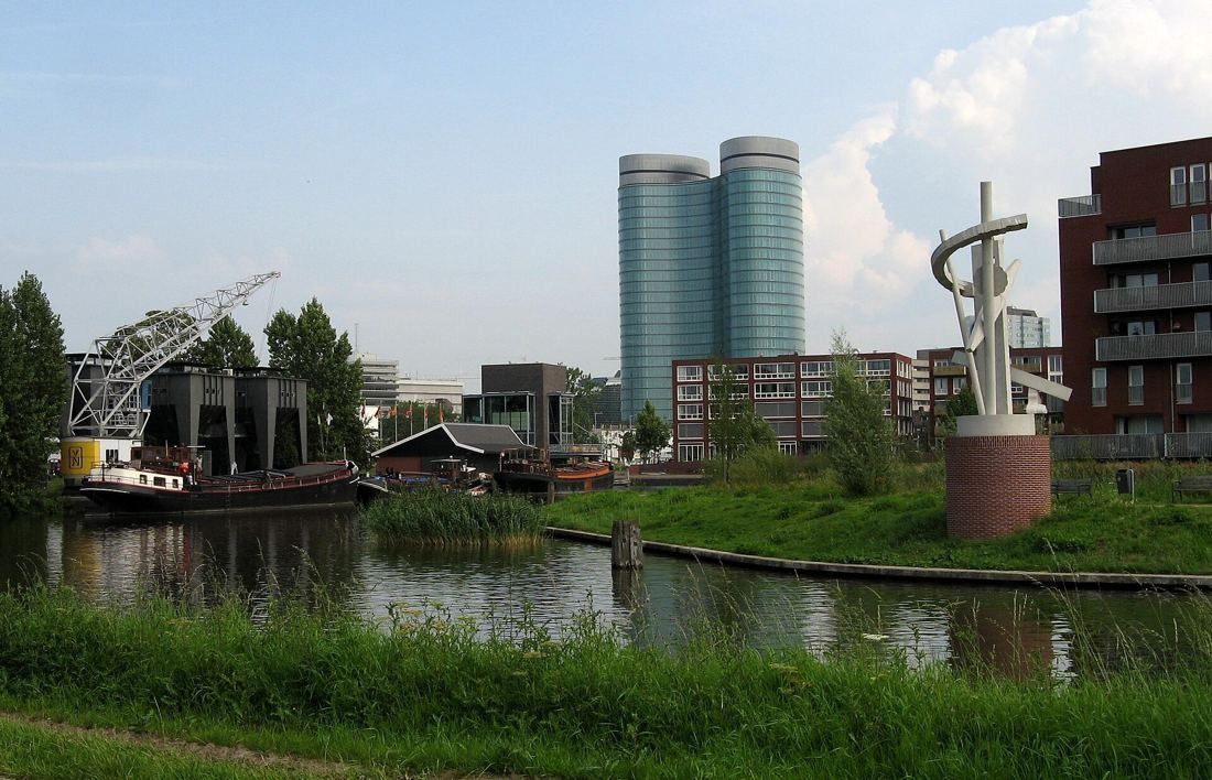 Rabobank: The two towers in the distance beyond a canal, boats and a white sculpture