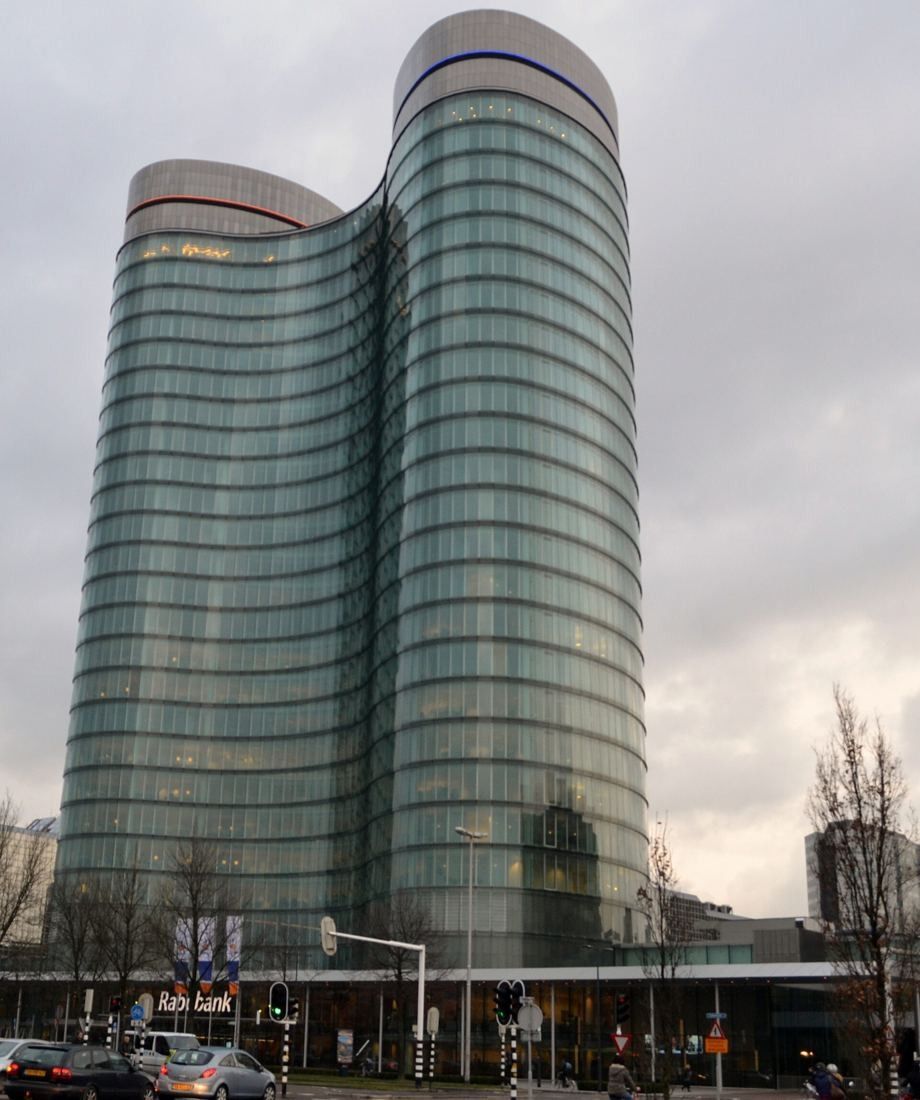 Rabobank: Two joined curved glass towers with horizontal bands, seen from street level