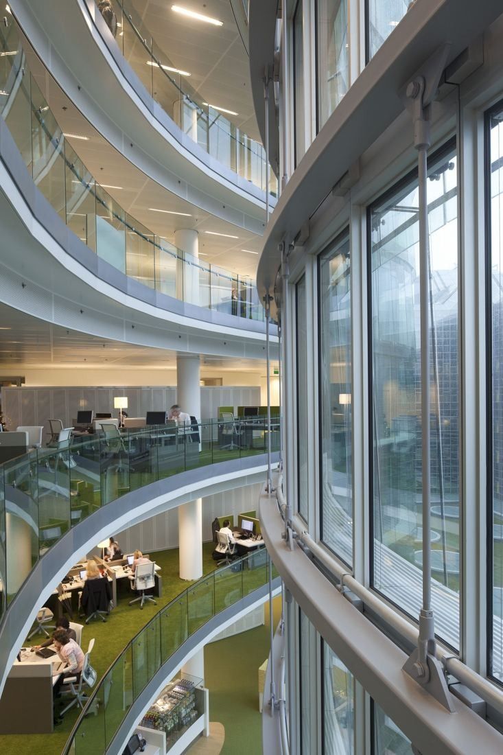 Rabobank: View down a multi-storey void lined with curved glass balustrades, with desk areas on each floor beside the glass facade