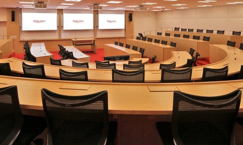 Rakuten Group: Curved rows of desks in a lecture hall facing screens