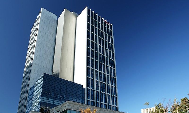 Glass office tower with a white vertical fin against a blue sky